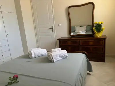 a bedroom with a bed with towels and a mirror at Maria's Apartment Next to Alimos Metro Station in Athens