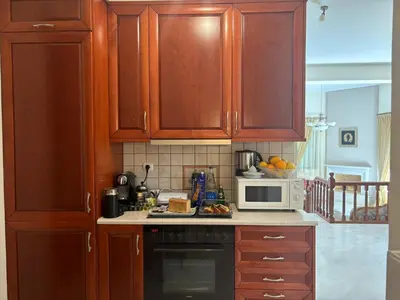 a kitchen with wooden cabinets and a microwave at Maria's Apartment Next to Alimos Metro Station in Athens