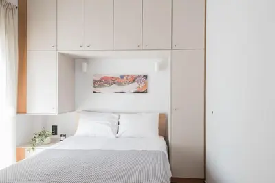 a bedroom with a white bed and white cabinets at Sunlight rooftop apartment in Athens