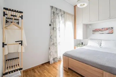 a white bedroom with a bed and a window at Sunlight rooftop apartment in Athens