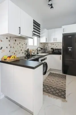 a kitchen with white cabinets and a black refrigerator at Sunlight rooftop apartment in Athens