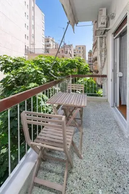 a wooden chair sitting on a balcony with a table at Sea Breeze 2 bedroom Apartment - 10 min walk to beach in Athens