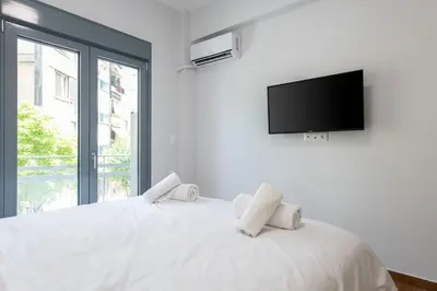 a bedroom with a white bed with a flat screen tv at SoulPoint Near City in Athens