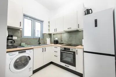 a kitchen with white cabinets and a washer and dryer at SoulPoint Near City in Athens