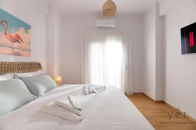 a white bedroom with a large white bed and a window at Free-Spirit Large Boho Apartment with Free-Parking in Athens