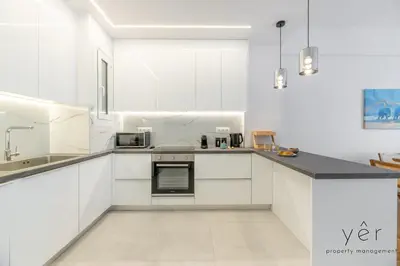 a white kitchen with white cabinets and a sink at Free-Spirit Large Boho Apartment with Free-Parking in Athens