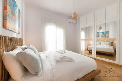 a white bedroom with a bed and a mirror at Free-Spirit Large Boho Apartment with Free-Parking in Athens