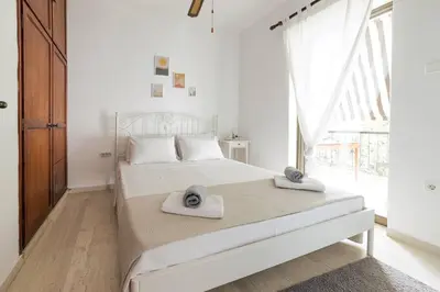 a white bedroom with a bed with towels on it at Seaside escape apartment in Saronida