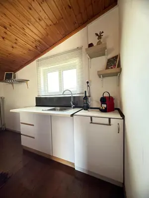 a kitchen with white cabinets and a sink and a window at Boomers Attic Athens in Koropíon
