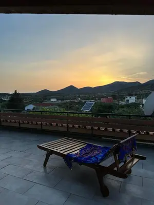 a bench sitting on top of a roof with the sunset at Boomers Attic Athens in Koropíon
