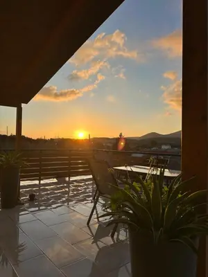 a sunset from the deck of a house with a table at Boomers Attic Athens in Koropíon