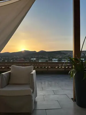 a white chair sitting on a balcony with a sunset at Boomers Attic Athens in Koropíon