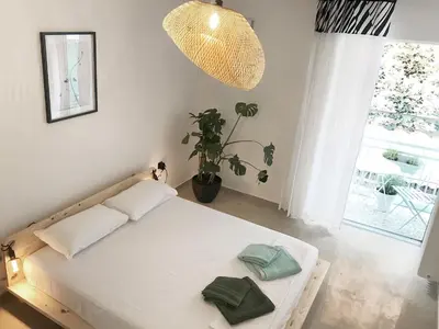 a white bed in a room with a potted plant at Zorba Meets Buddha in Athens