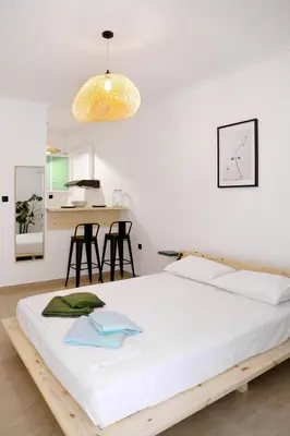 a bedroom with a large white bed and a kitchen at Zorba Meets Buddha in Athens