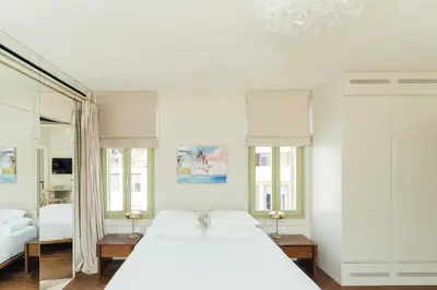 a white bedroom with a large bed and a mirror at Nosteo in Athens