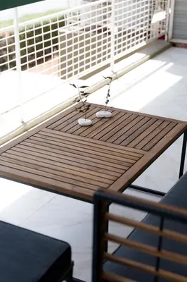 a wooden table with two chairs on a balcony at Sandlight Apartment by A&D Properties in Porto Rafti
