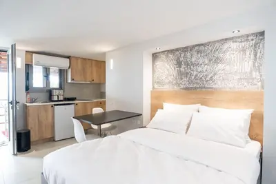 a bedroom with a white bed and a kitchen at Tranquility 248 in Athens