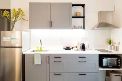 a kitchen with white cabinets and a stainless steel refrigerator at Urban Nights Athens in Athens