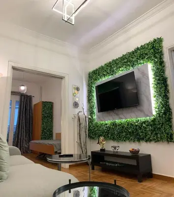 a living room with a tv on a wall with ivy at Athens Flower Paradise near Acropoli in Athens