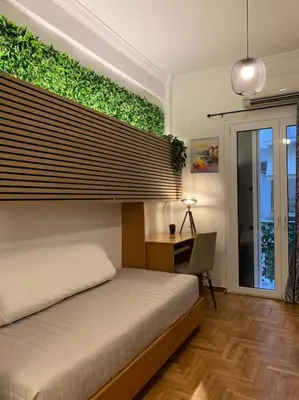 a bedroom with a bed and a desk with a green wall at Athens Flower Paradise near Acropoli in Athens