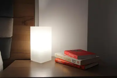 a stack of books sitting on a table with a lamp at 