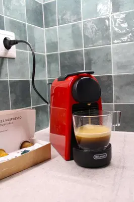 a red coffee maker sitting on a counter with a cup of coffee at 