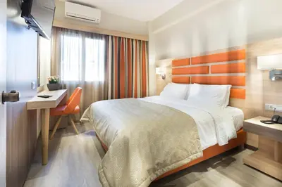 a hotel room with a large bed and a desk and a desk at Jason Inn in Athens