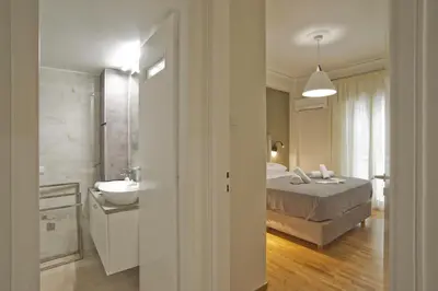 a bedroom with a bed and a bathroom with a sink at Fabi's Place Luxurious 2BR, Fully Renovated Apt in Athens