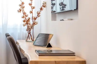 a laptop on a wooden table with a vase of flowers at Modern Studio in Syntagma - Walk to Acropolis in Athens