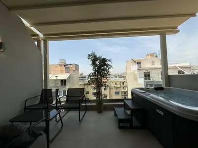 a balcony with a tub and chairs and a window at BlueMotion - CruiseNest 6Β in Piraeus
