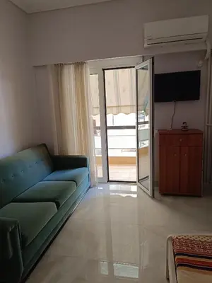 a living room with a blue couch and a television at Classical beauty near Acropolis! in Athens