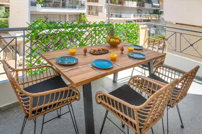 a wooden table with chairs and plates of food on a balcony at Luxurious Coastal Retreat in Central Glyfada in Athens