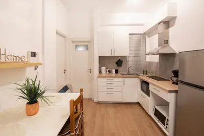 a kitchen with white cabinets and a table with a potted plant at Alkisti in Athens