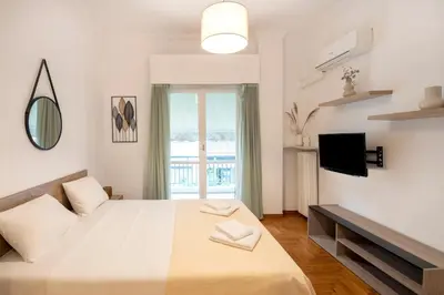 a white bedroom with a large bed and a tv at Alkisti in Athens