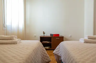 a room with two beds and a table with a window at Olvios Attiki Metro in Athens