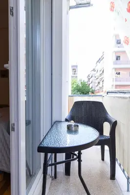 a small table and a chair on a balcony at Olvios Attiki Metro in Athens