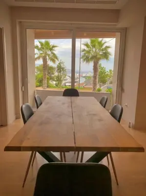a wooden table with chairs in a room with a large window at D-Marin Zea Marina 2 Bedroom in Piraeus