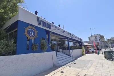 a blue building with a sign that reads vanguard at \u8ff7\u4eba\u82b1\u56ed\u516c\u5bd3 Charming Garden in Athens