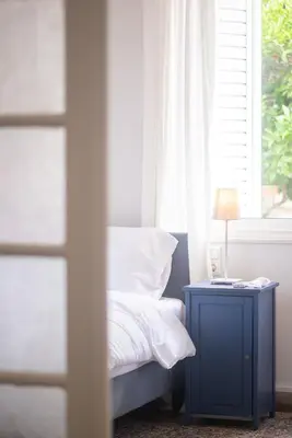 a bed with a blue nightstand next to a window at Bright & Cozy House near Beach in Athens