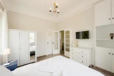 a white bedroom with a bed and a tv at Bright & Cozy House near Beach in Athens
