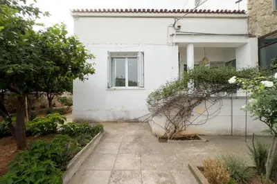 a white house with a garden in front of it at Bright & Cozy House near Beach in Athens