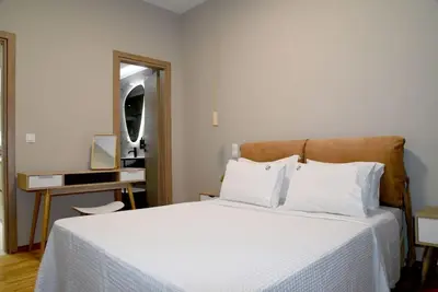 a bedroom with a bed with white sheets and a mirror at Elegant Central 2BR & 2 Ensuite Baths, Near Metro in Athens