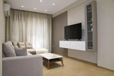 a living room with a white couch and a tv at Elegant Central 2BR & 2 Ensuite Baths, Near Metro in Athens
