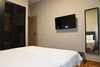 a bedroom with a white bed and a tv on the wall at Elegant Central 2BR & 2 Ensuite Baths, Near Metro in Athens
