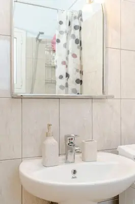 a bathroom with a white sink and a mirror at Seaside Escape Apartments - Poseidon in Palaiá Fókaia