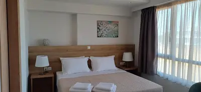 a bedroom with a bed with two lamps and a window at ALPHA APARTMENTS Free Shuttle from and to the Airport in Spáta