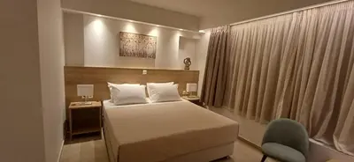 a hotel room with a bed and a chair at ALPHA APARTMENTS Free Shuttle from and to the Airport in Spáta