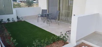 a patio with a table and chairs and grass at ALPHA APARTMENTS Free Shuttle from and to the Airport in Spáta
