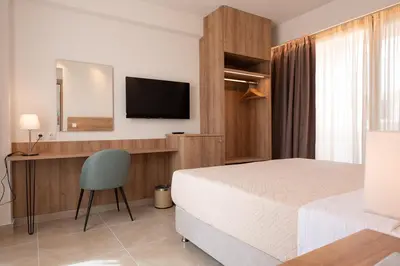a bedroom with a bed and a desk and a television at ALPHA APARTMENTS Free Shuttle from and to the Airport in Spáta