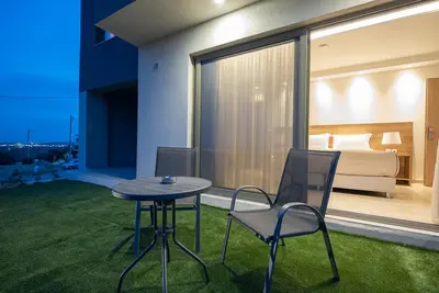 a room with a table and chairs and a bedroom at ALPHA APARTMENTS Free Shuttle from and to the Airport in Spáta